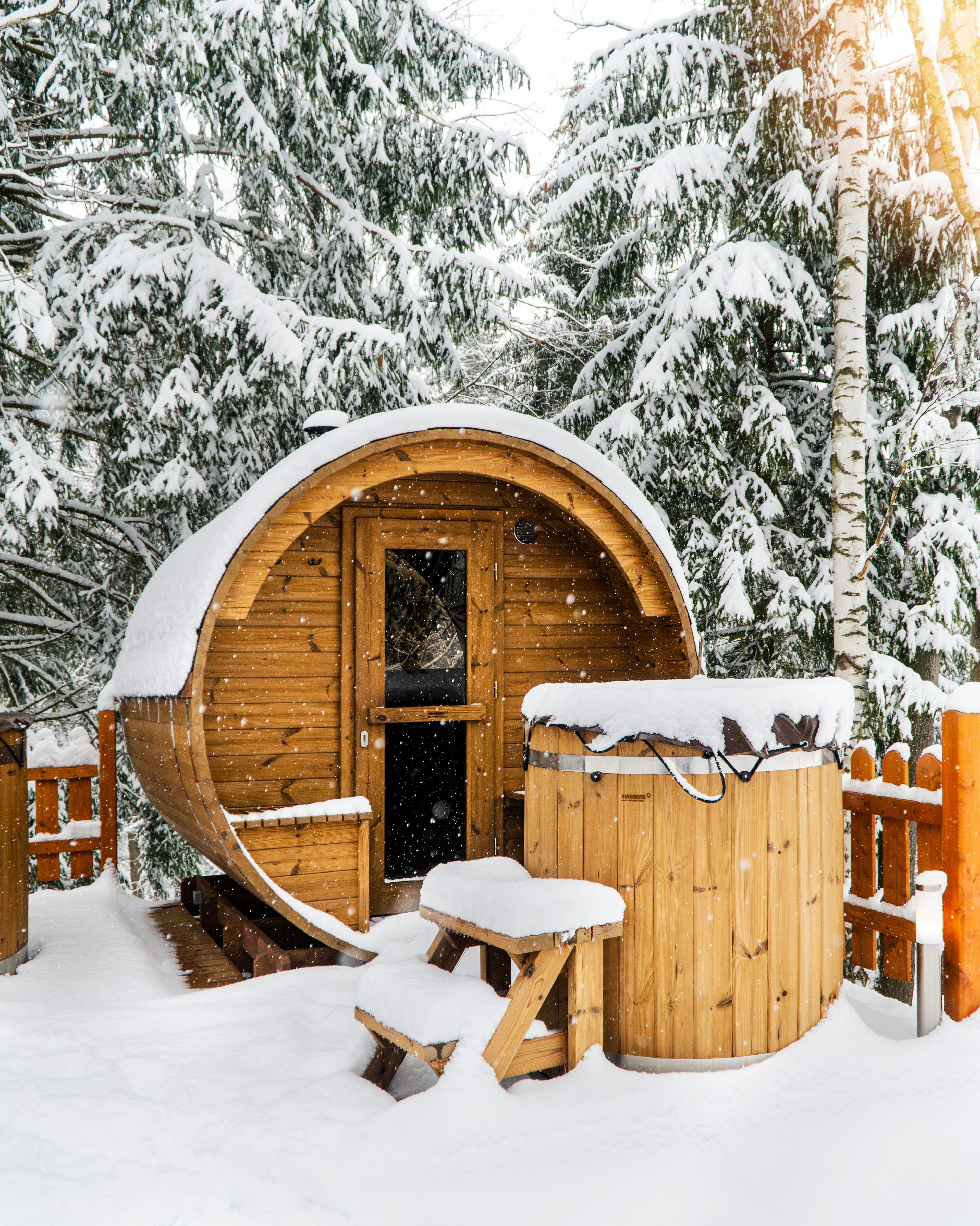 Barrel sauna covered in snow in a winter forest