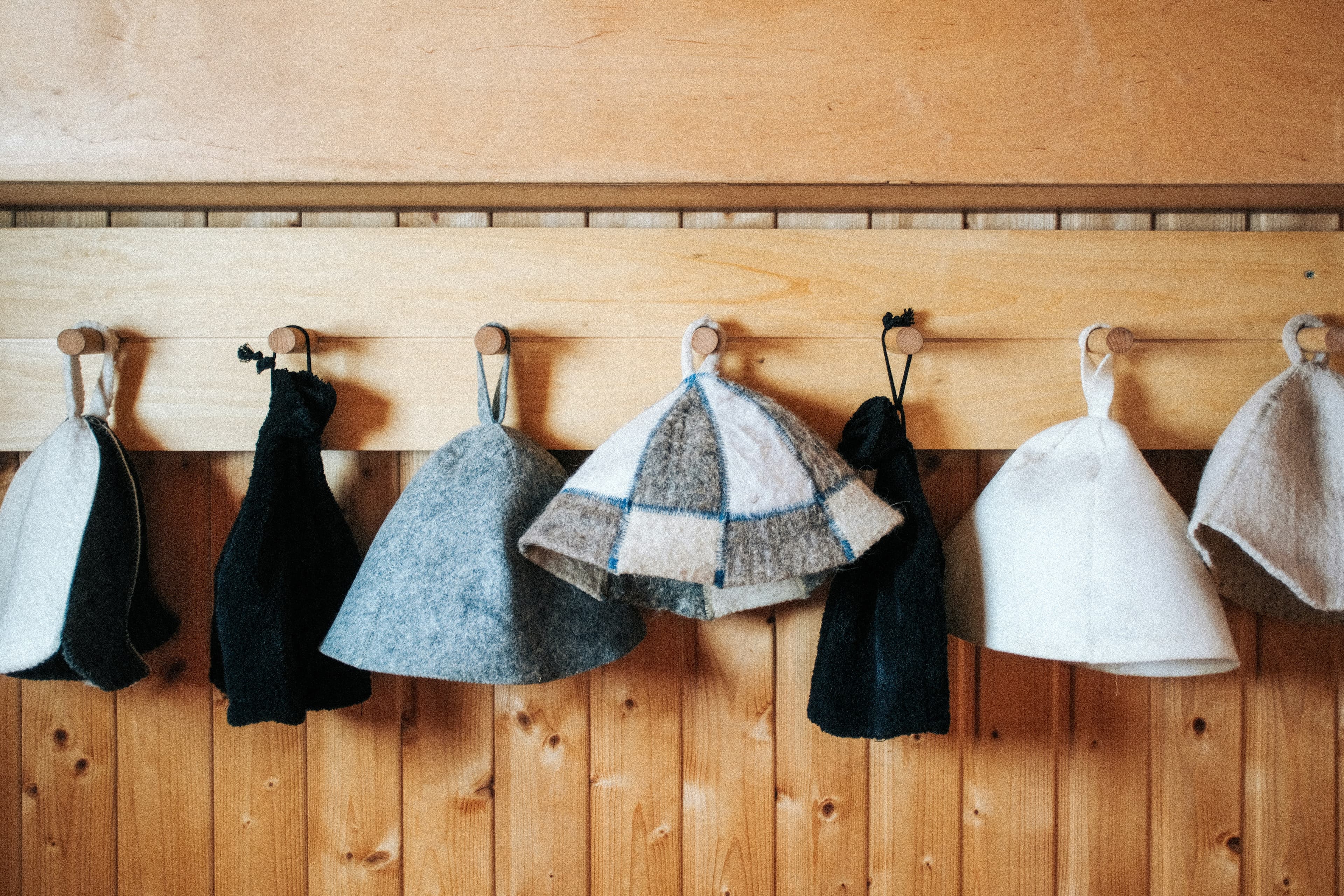 Traditional wool felt sauna hats hanging on wooden hooks